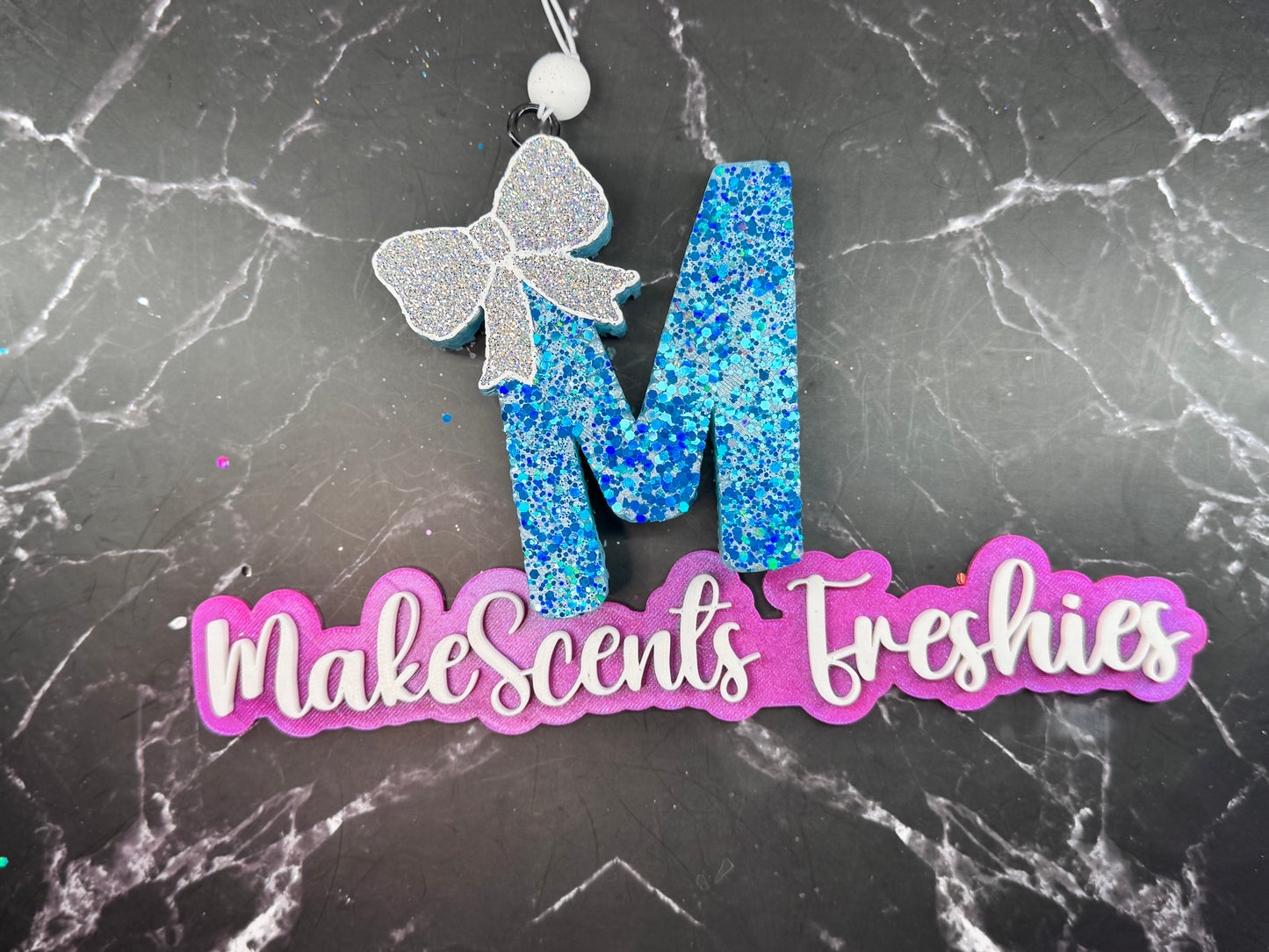 "M" with a bow